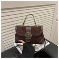Detail der dunkelbraunen Wildledertasche mit großer Goldschnalle und weißen Kontrastnähten - Kaffeebraun