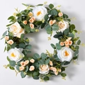 Close-up of artificial white roses and eucalyptus leaves on a lush decorative wreath - Rose Camellia Mixed Wreath