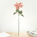 Détail d'un poinsettia artificiel rose avec pétales soyeux et feuilles sur table en bois - Rose