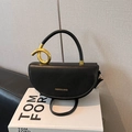Bolso montura minimalista de cuero negro con asa metálica dorada anudada distintiva - Negro