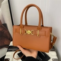 Bolso bandolera marrón rectangular con hebilla de corazón dorado sobre maleta blanca - Marrón Oscuro