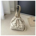 Detail of corduroy bucket bag with brown bow patterns and woven carry handles - White