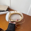 White semi-circular crossbody bag with gold oval handle and chain strap on wood background - White