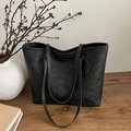 Classic black tote bag with quilted texture and dual straps in a stylish interior setting - Black