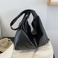 Detalle de un bolso hobo negro con correa anudada sobre un fondo de abrigo de lana - Negro