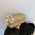 Detalle de bolso beige con hebilla en D dorada y pañuelo de seda elegante decorativo - Verde