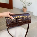 Detalle de bolso baguette marrón oscuro con relieve de cocodrilo y hebilla pulida - Marrón
