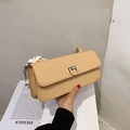 Detalle de un elegante bolso baguette de cuero crema con cierre dorado y bufanda de seda - Caqui