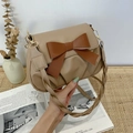 Dettaglio borsa beige a pieghe con grande fiocco marrone e tracolla in pelle intrecciata - Cachi