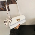 Detalle de bolso baguette blanco con cierre dorado y bufanda de seda con diseño H - Blanco