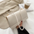 Beige Tasche mit Krokodilmuster und goldenen Details auf einem stilvollen Hintergrund - Weiß