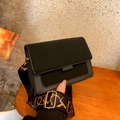 Detalle de bolso bandolera negro con hebilla dorada y correa tejida con diseño de letras - Negro