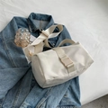 Minimalistische weiße Nylon-Umhängetasche mit breitem Gurt und Schnalle auf Denim-Jacke - Weiß