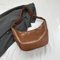 Retro brown PU leather crescent hobo bag with adjustable strap on grey blazer background - Tan