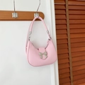 Bolso de hombro rosa tipo media luna con lazo plateado colgado en gancho madera - Rosa