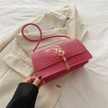 Sac à épaule magenta en similicuir crocodile avec logo doré et pompon chic - Rose