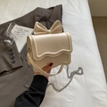 Beige crossbody bag with bow detail and wavy flap on a gray blazer background - Off-white