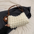 White waffle textured shoulder bag with brown handle and floral charm on a navy blazer - White and Brown