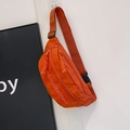 Detail view of orange nylon chest bag featuring textured letter printing and woven zipper pull - Orange