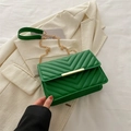 Green quilted leather crossbody bag with gold chain strap on a white blazer - Green