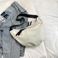 Bolso bandolera blanco de media luna con correa negra sobre fondo denim informal - Blanco