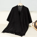 Detailansicht eines schwarzen Strickponchos mit Hohlmustern und eleganten Fransenakzenten - Buchstabe F / Schwarz