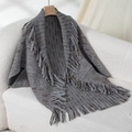 Poncho de punto gris con flecos y textura moteada marrón en percha de madera - Letra F / Gris
