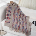 Poncho in maglia beige con cappuccio, strisce colorate e frange su un divano morbido - Lettera F / Cachi