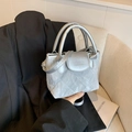Bolso saco acolchado plateado con brillo metálico y correa sobre chaqueta negra - Plateado