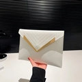 White faux leather envelope clutch featuring V-shaped gold metal trim and quilted details - White