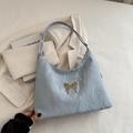 Light blue shoulder tote bag featuring textured fabric and a silver metal butterfly - Blue