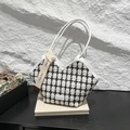 Elegante schwarz-weiße Tweed-Handtasche mit Schleifenband auf cremefarbenen Büchern - Weißer Gitter
