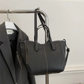Black litchi grain leather tote bag featuring striking white contrast stitching and dual handles - Black