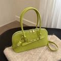Retro hellgrüne Lederhandtasche mit Doppelgriffen und Goldschnallen auf weicher Strickdecke - Grün