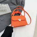 Sac bandoulière orange avec fermoir cœur doré et poignée plissée sur fond gris - Orange