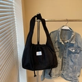 Black corduroy tote bag with drawstring closure and white label in a casual setting - Black