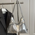 Silberne Metallic-Schultertasche mit Schleifen und Doppelreißverschluss auf dunkler Jacke - Silber
