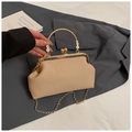 Detail der gewebten Strohhandtasche mit Gänseblümchen-Anhänger und goldener Kette - Khaki