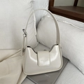 Chic cream white leather hobo underarm bag with adjustable strap on a book background - White