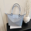 Minimalist light blue large nylon tote bag with leather handles in a home setting - Blue