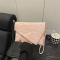 Pink envelope clutch bag with pleated texture and gold metal bar detail in hand - Pink