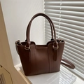 Borsa tote minimalista in pelle marrone con manico e tracolla su un libro bianco - Marrone