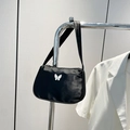 Minimalist black satin underarm bag with a white butterfly metal buckle on display - Black