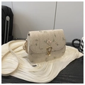 Detailed view of floral embroidery and gold droplet lock on a woven saddle bag - White