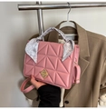 Detailed view of pink quilted handbag featuring a scarf-wrapped handle and gold twist lock - Pink