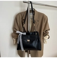 Detail einer schwarzen matten Ledertasche mit goldenem Drehverschluss und weißer Spitzenschleife - Schwarz