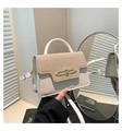 Détail d'un sac à main en cuir contrasté avec boucle métallique sur un fond minimaliste - Blanc