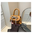 Dettaglio macro di una mini borsa giallo senape con fibbia a fiocco in strass lucidi - Marrone