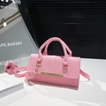 Chic pink faux leather handbag with gold metal bar and adjustable strap seen from 45-degree angle - Pink