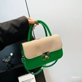 Green leather handbag with beige woven flap and gold T-lock shown in hand - Green